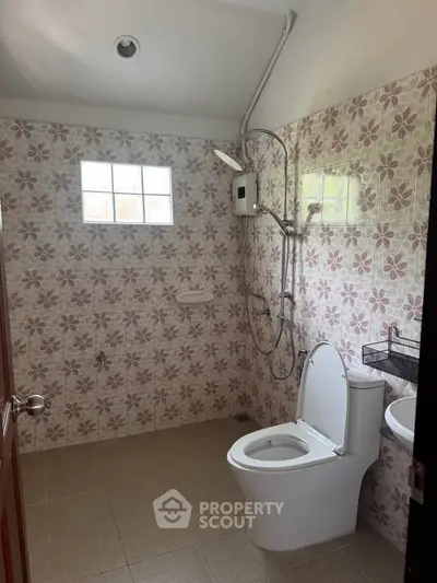 Spacious bathroom with floral tiles and modern fixtures in a well-lit setting.