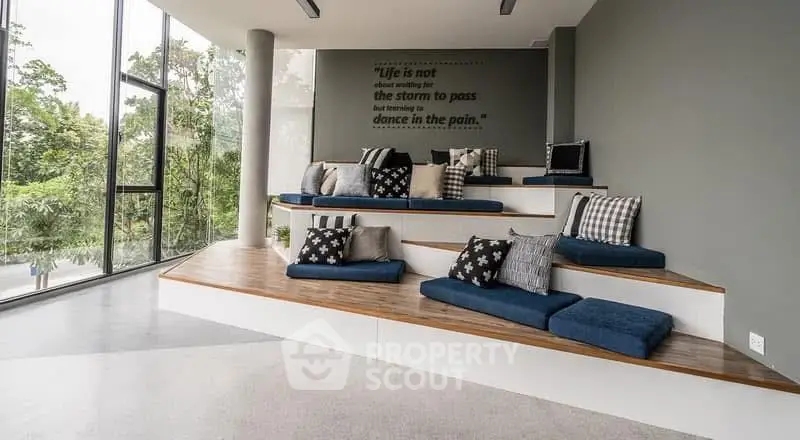 Modern communal area with tiered seating and large windows overlooking greenery.