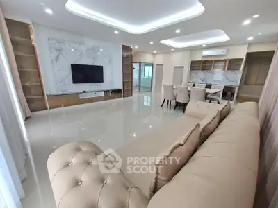 Luxurious modern living room with elegant beige sofa, marble TV wall, and open dining area.