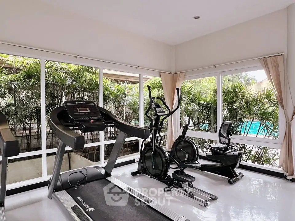Bright home gym with modern equipment and pool view, ideal for fitness enthusiasts.