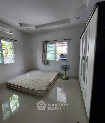Spacious bedroom with natural light, featuring a minimalist design and large wardrobe.