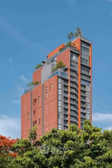 Stunning modern high-rise building with lush rooftop gardens and vibrant orange facade.