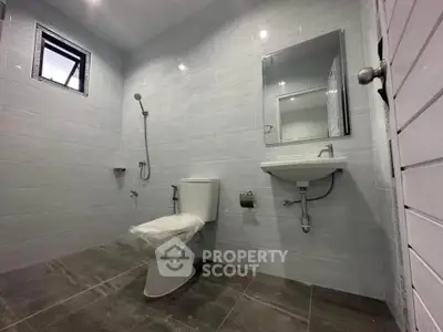 Modern bathroom with sleek fixtures and minimalist design, featuring a wall-mounted sink and shower.