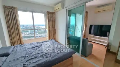 Spacious bedroom with stunning city view and adjacent living area in modern apartment.