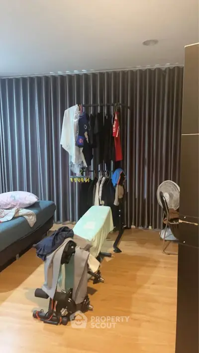 Cozy bedroom with clothes rack and ironing board, ideal for practical living.