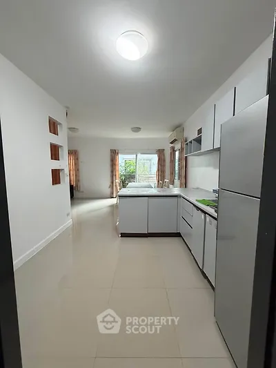Spacious kitchen with modern appliances and open layout leading to a bright living area.
