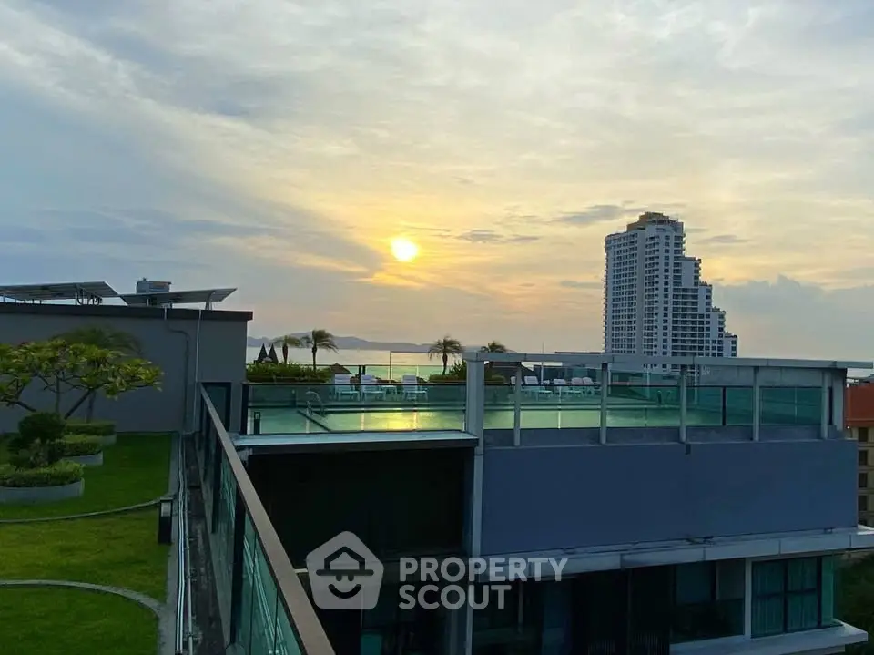 Stunning rooftop view with pool and sunset over city skyline.