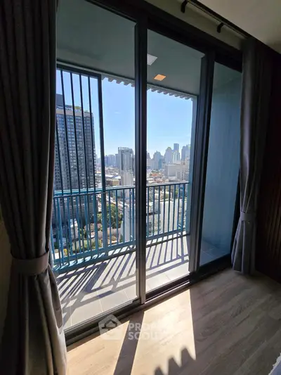 Stunning city view from modern apartment balcony with floor-to-ceiling windows.