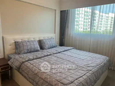 Spacious bedroom with modern decor and large window offering natural light and city view.