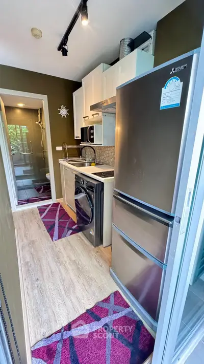 Compact kitchen with modern appliances and washing machine, featuring stylish decor and efficient layout.