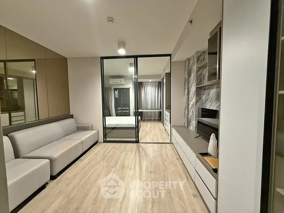 Modern living room with sleek design and glass partition leading to bedroom
