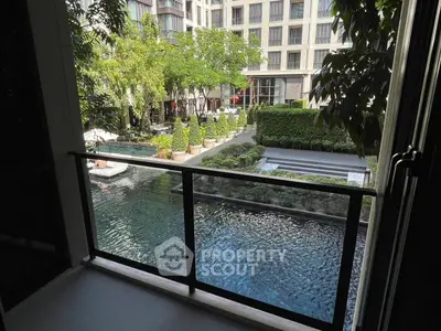 Luxurious balcony view overlooking serene pool and lush garden in modern apartment complex.