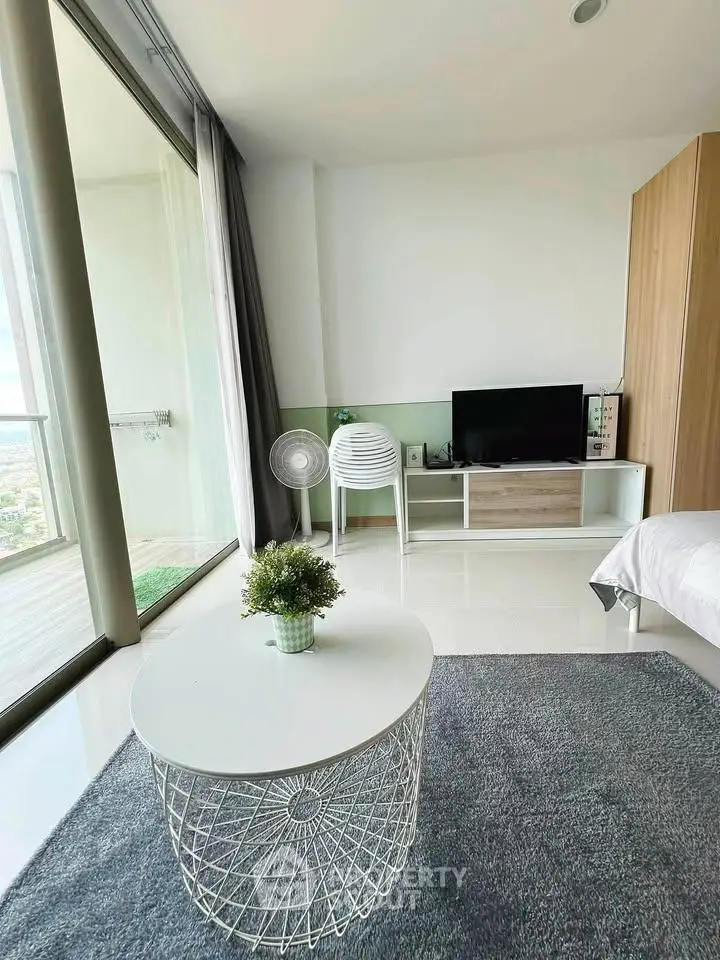 Modern living room with balcony view, stylish furniture, and natural light