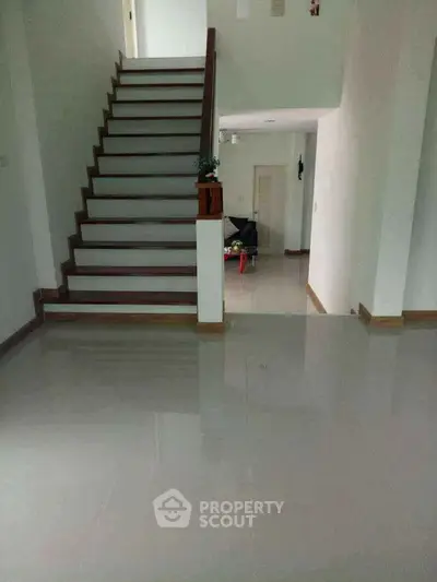 Spacious modern interior with sleek staircase and glossy tiled flooring, perfect for contemporary living.