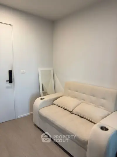 Cozy small living room with modern beige sofa and wall mirror