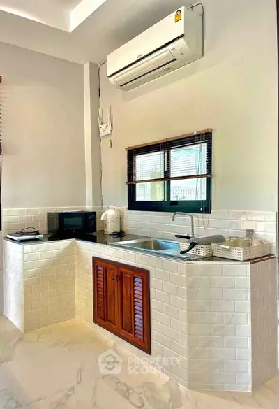 Modern kitchen with sleek white tiles, air conditioning, and wooden cabinets.