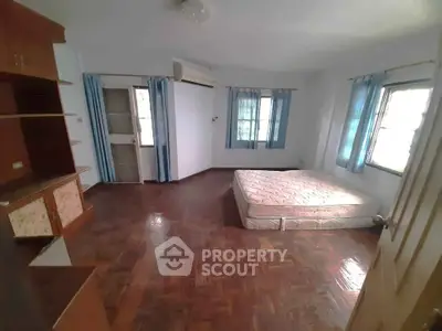Spacious bedroom with parquet flooring and large windows for natural light.