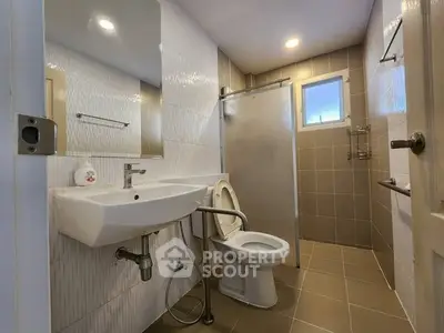 Modern bathroom with sleek fixtures and neutral tiles, featuring a spacious shower area.