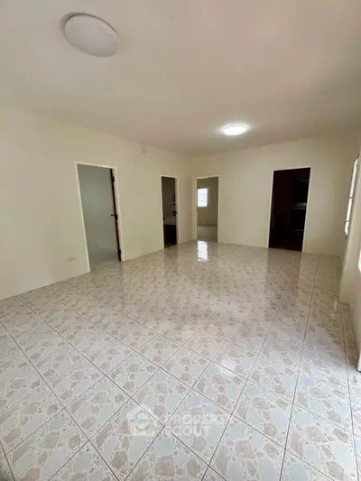 Spacious tiled living room with multiple doorways and natural light