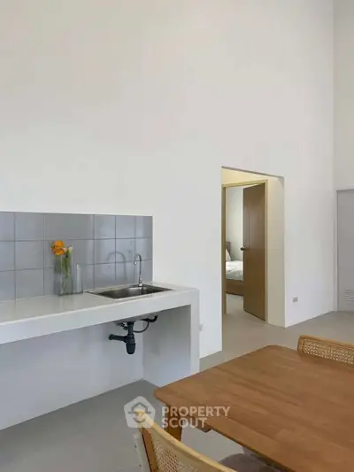 Modern minimalist kitchen with open layout and dining area, featuring sleek design and natural light.