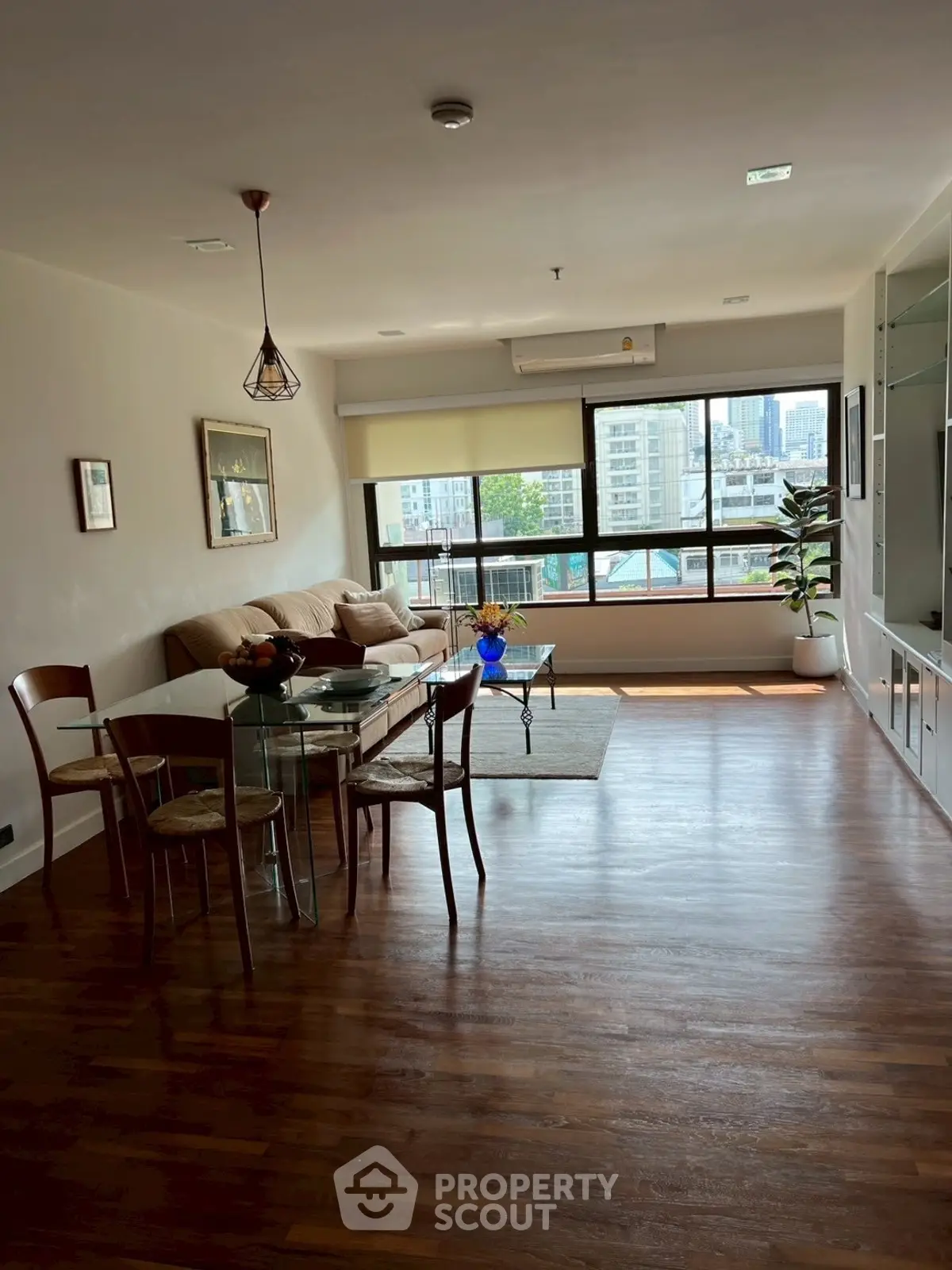 Spacious living room with wooden flooring and city view, perfect for modern living.