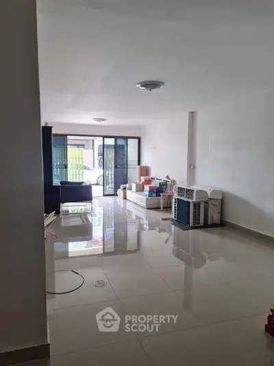 Spacious living room with glossy tiled floors and sliding glass doors leading to a patio.