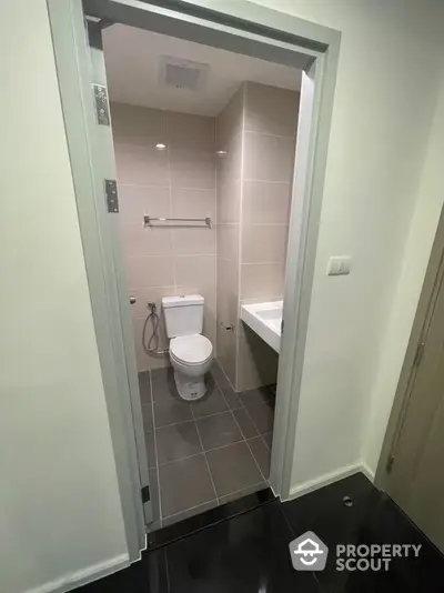 Modern bathroom with sleek design and tiled walls, featuring a toilet and sink.