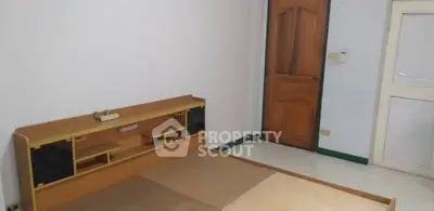 Spacious bedroom with wooden bed frame and door, ideal for customization.