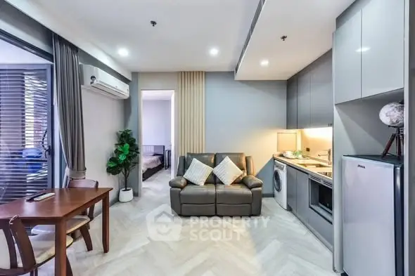 Modern open-plan living room with kitchen, featuring sleek design and cozy ambiance.