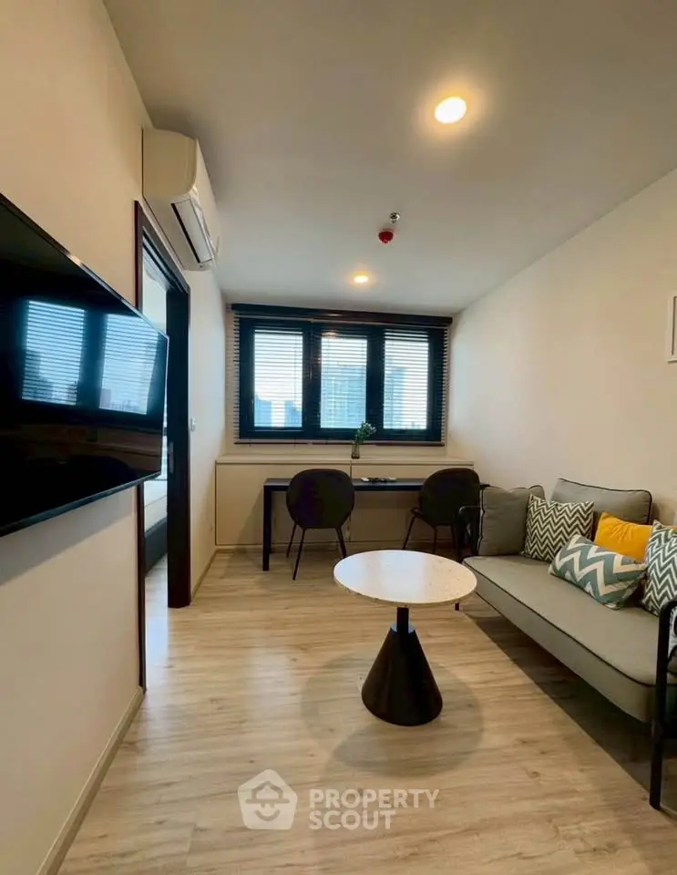 Modern living room with stylish decor and natural light, featuring a cozy sofa and a sleek wall-mounted TV.