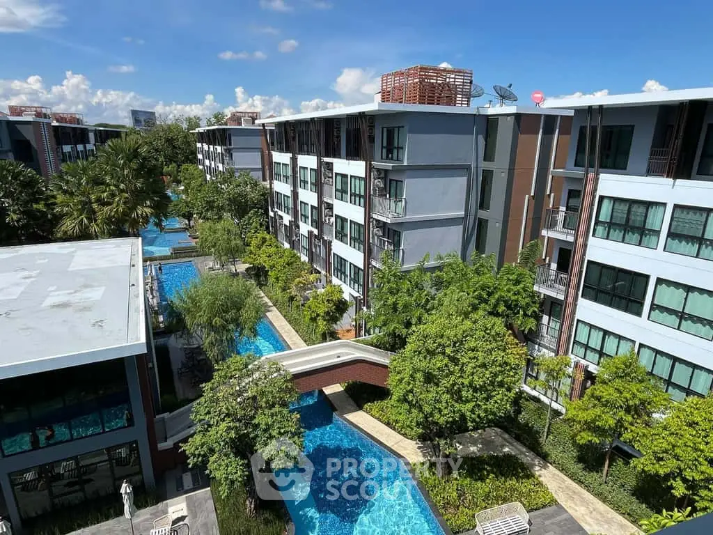 Luxurious condominium complex with stunning pool and lush greenery, offering a serene and modern living environment.