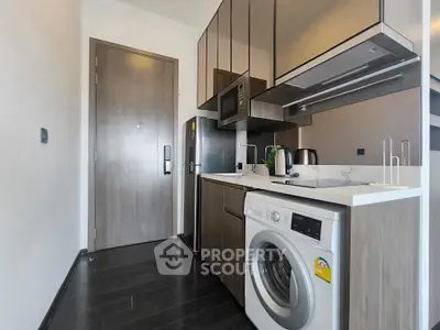 Modern kitchen with sleek appliances and washing machine in compact layout.