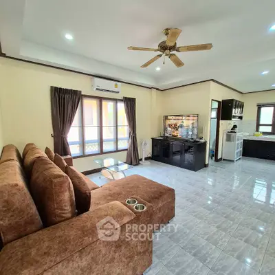 Spacious living room with modern furniture and ceiling fan in a bright home.