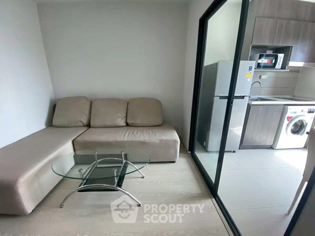 Modern compact living room with glass table and kitchen view