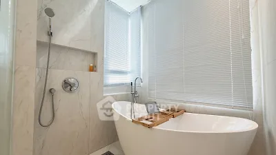 Luxurious bathroom with freestanding tub and modern fixtures in elegant marble setting.