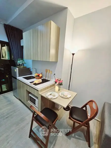 Modern compact kitchen with stylish wooden cabinets and cozy dining area in a chic apartment.