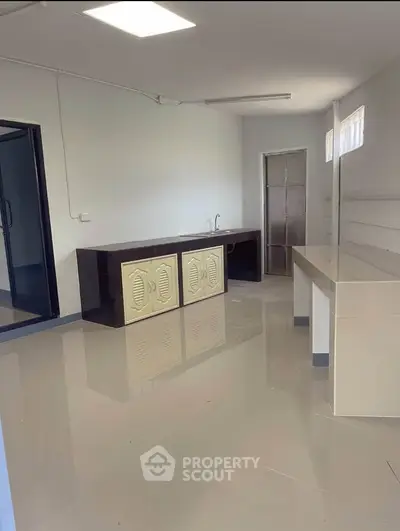 Spacious kitchen with sleek countertops and ample storage in modern apartment.