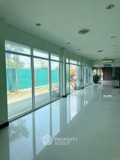 Spacious commercial space with large windows and glossy floors, ideal for retail or office use.