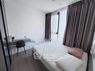 Modern bedroom with large window and stylish decor in a contemporary apartment.