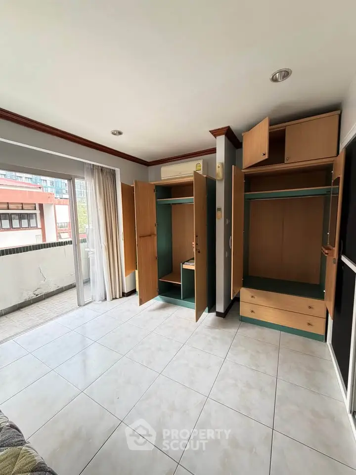 Spacious bedroom with built-in wardrobes and balcony access in modern apartment.