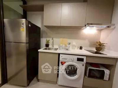 Modern kitchen with sleek appliances including fridge, washing machine, and microwave.