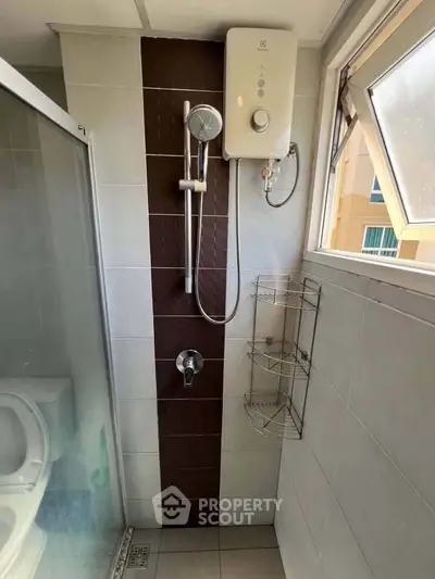 Compact bathroom with shower and water heater, featuring modern tile design and natural light.