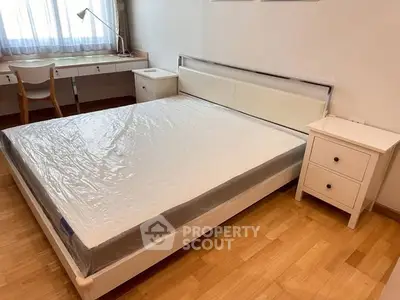 Spacious bedroom with modern furniture and natural light, featuring a large bed and study desk.