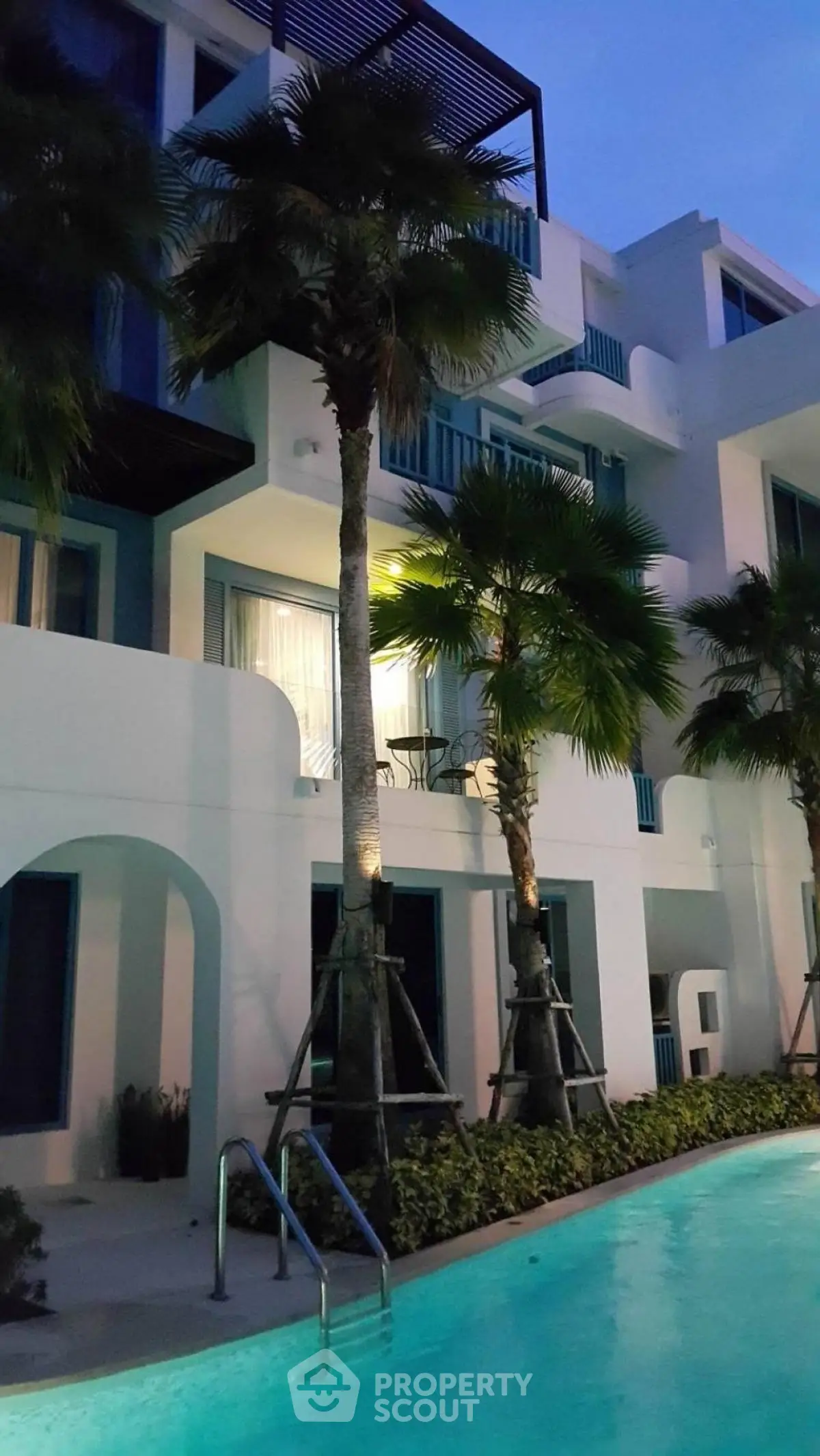 Luxurious modern apartment with poolside view and palm trees at dusk