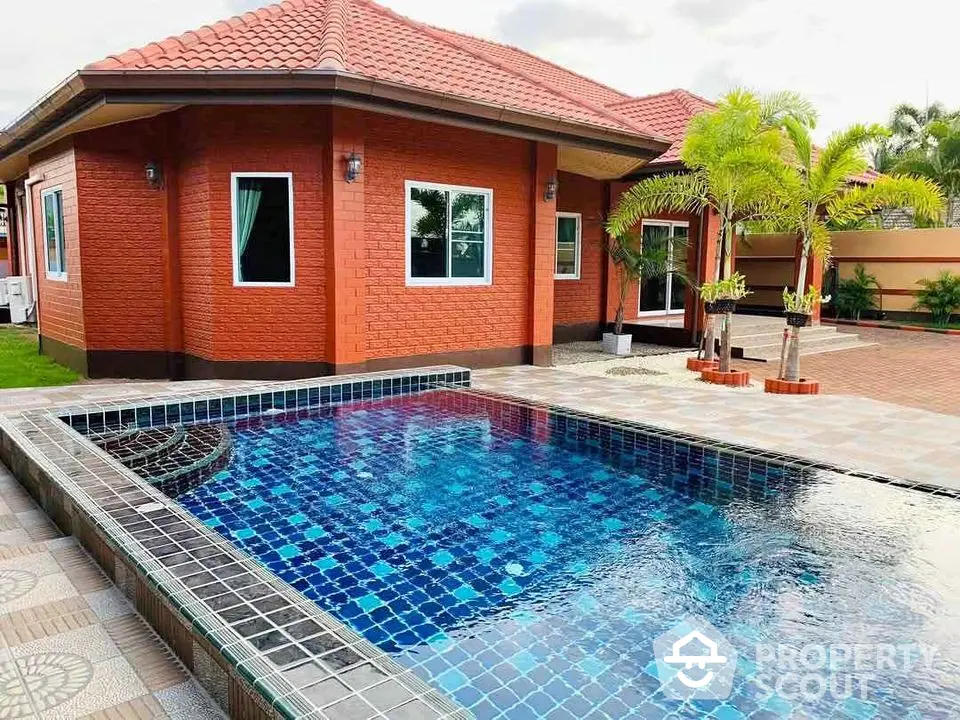 Charming red-brick house with a stunning blue-tiled pool and lush palm trees, perfect for relaxation.