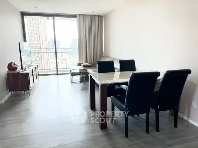 Modern living room with sleek furniture and city view balcony in high-rise apartment.