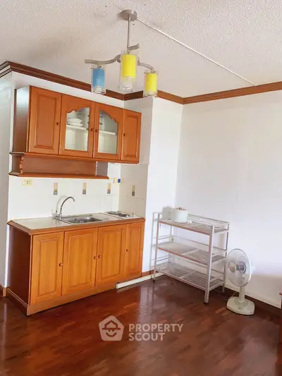 Charming kitchen with wooden cabinets and modern lighting in cozy apartment.