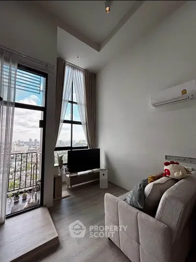 Modern living room with balcony and city view, featuring sleek furniture and large windows.