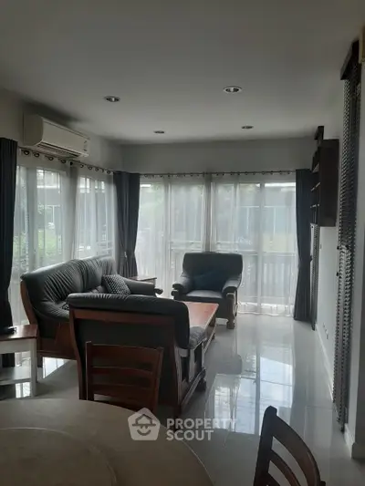 Spacious living room with large windows and elegant furniture, perfect for relaxation and entertaining.