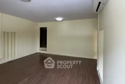 Spacious empty room with wooden flooring and air conditioning, ideal for customization.